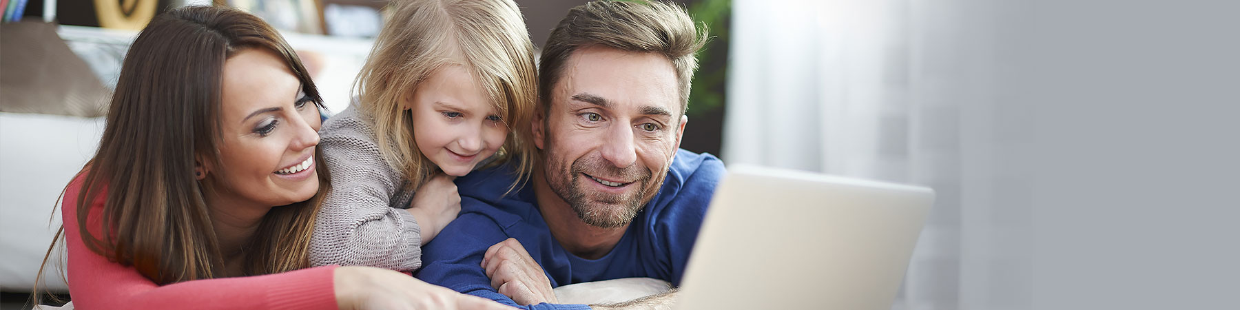 Family sitting down at laptop to register online for recreation programs